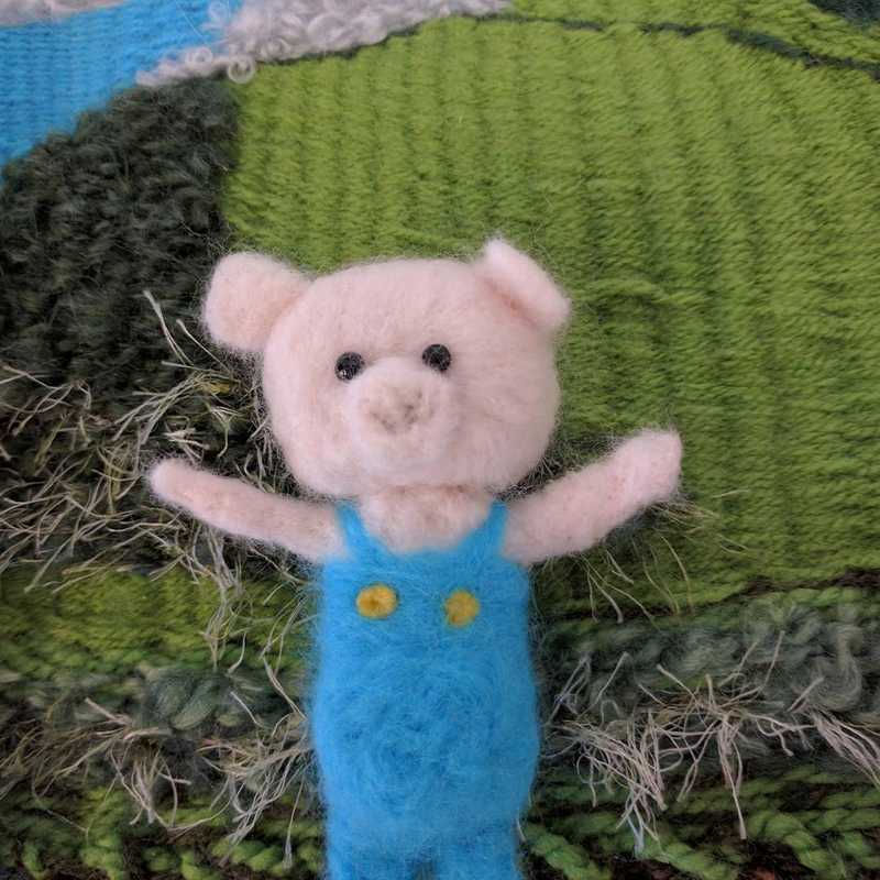 Needle felted pig with a weaved background.